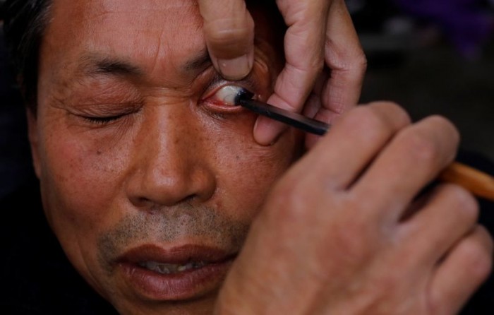 Китайский уличный парикмахер бреет глаза клиентов опасной бритвой