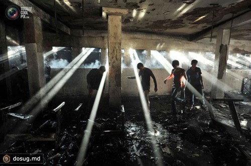 Люди ищут уцелевшие вещи после пожара на швейной фабрике в Дакке, Бангладеш.