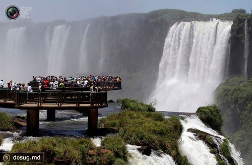 Туристы стоят на смотровой площадке возле водопада в национальном парке Игуасу, Аргентина.